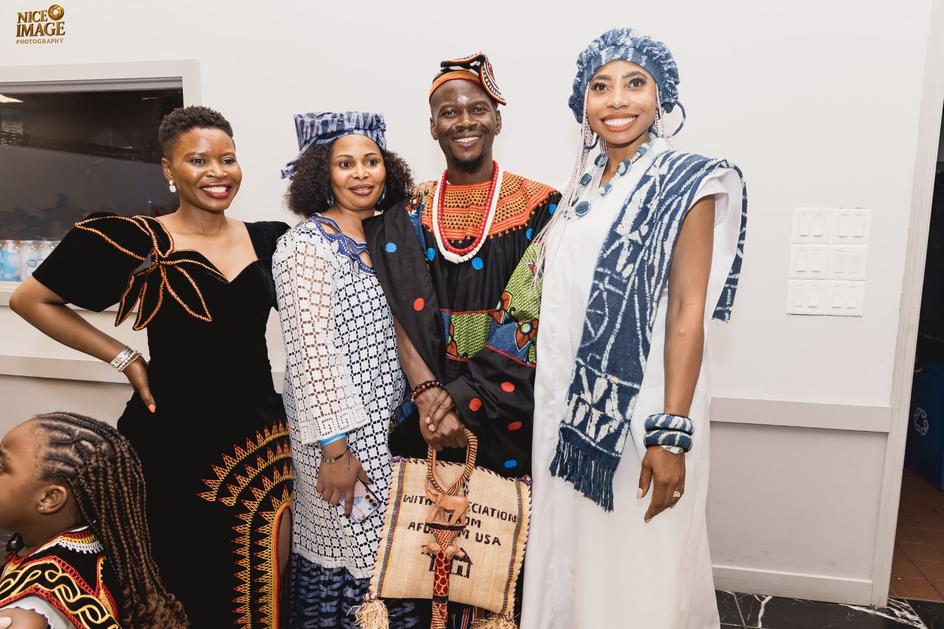 Four smiling adults in traditional Cameroonian attire pose together at a BotangRecords event, with a young girl visible nearby.