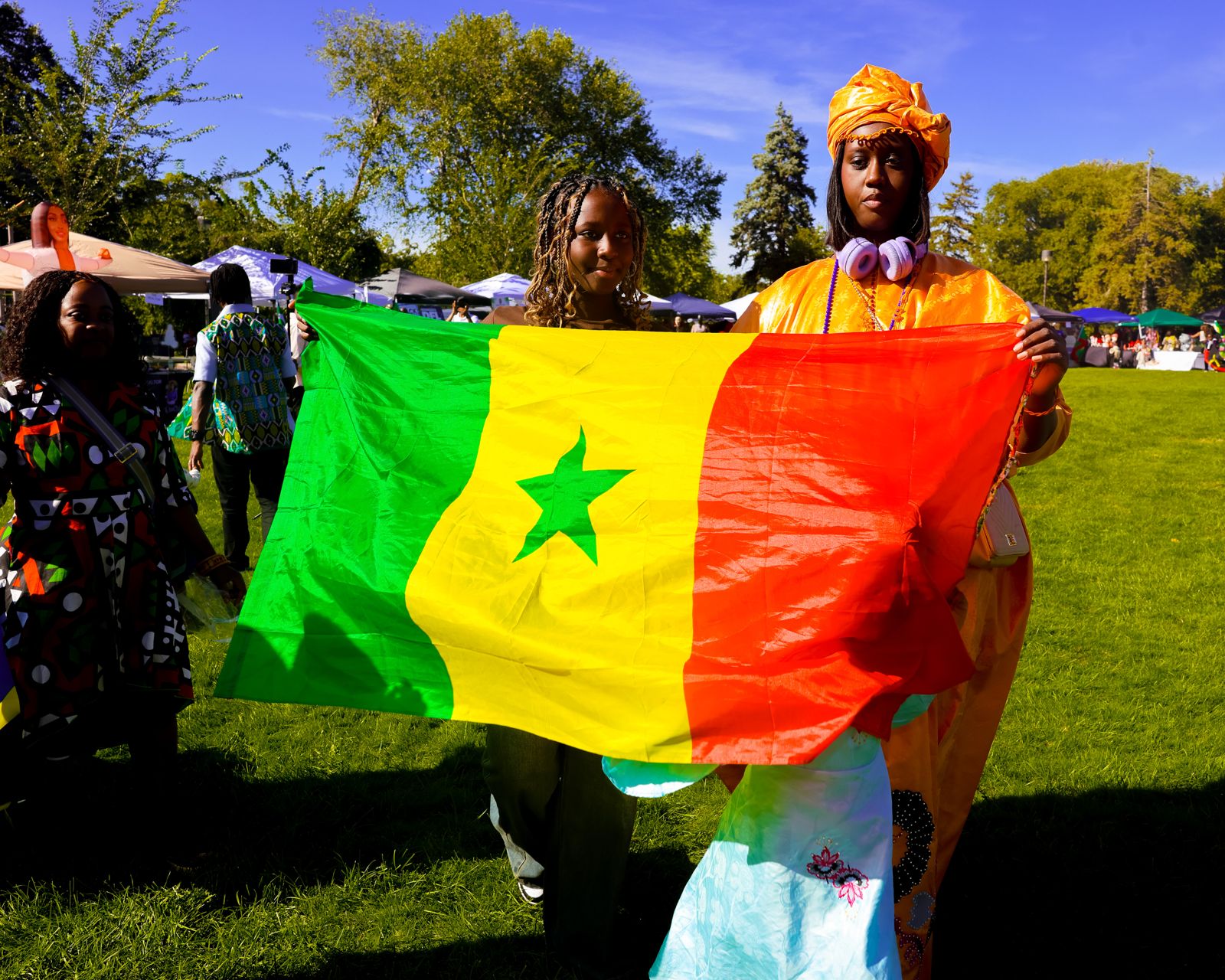A woman in a gold head wrap and a young girl holding the Senegal flag