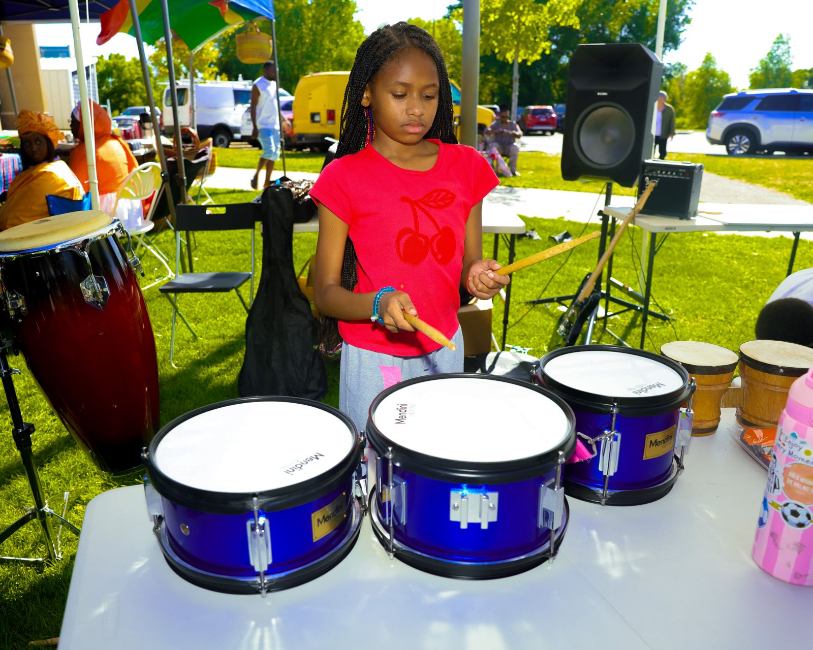A girl playing a set of blue drums at the instrument stand