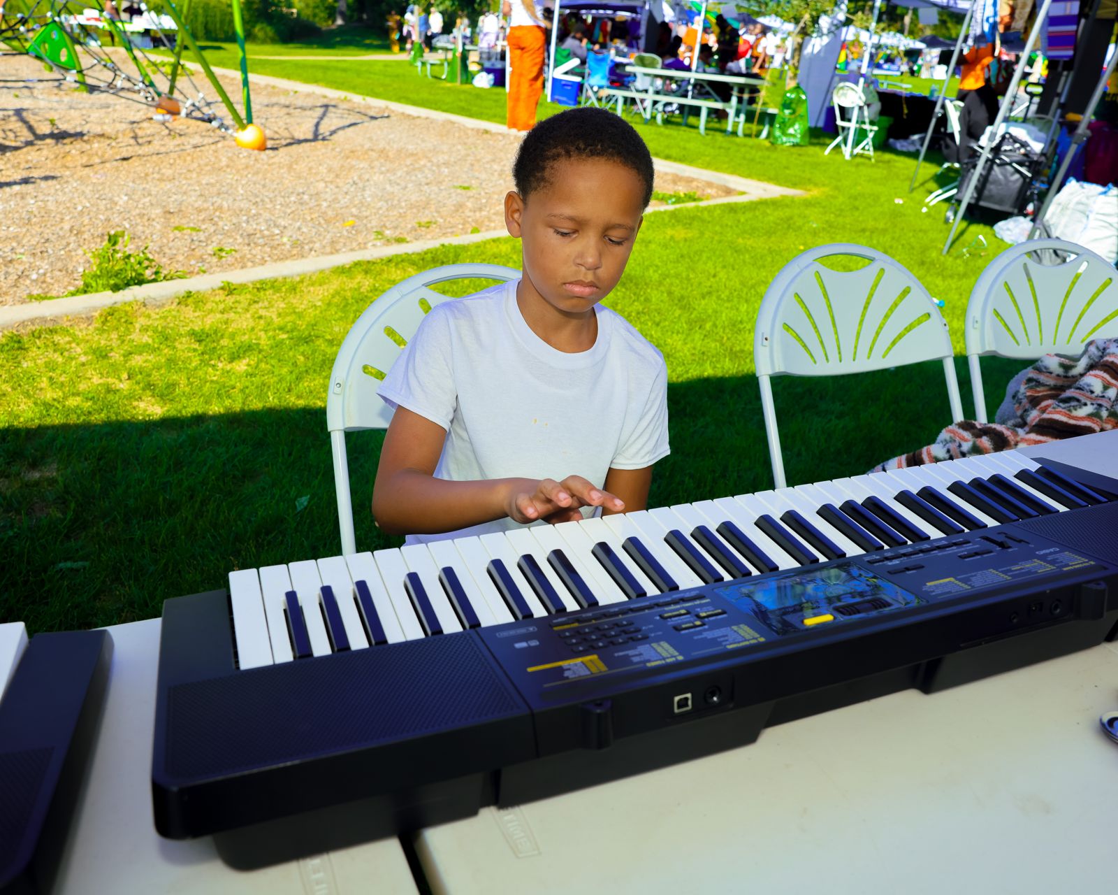 A boy playing an electronic keyboard at the instrument stand