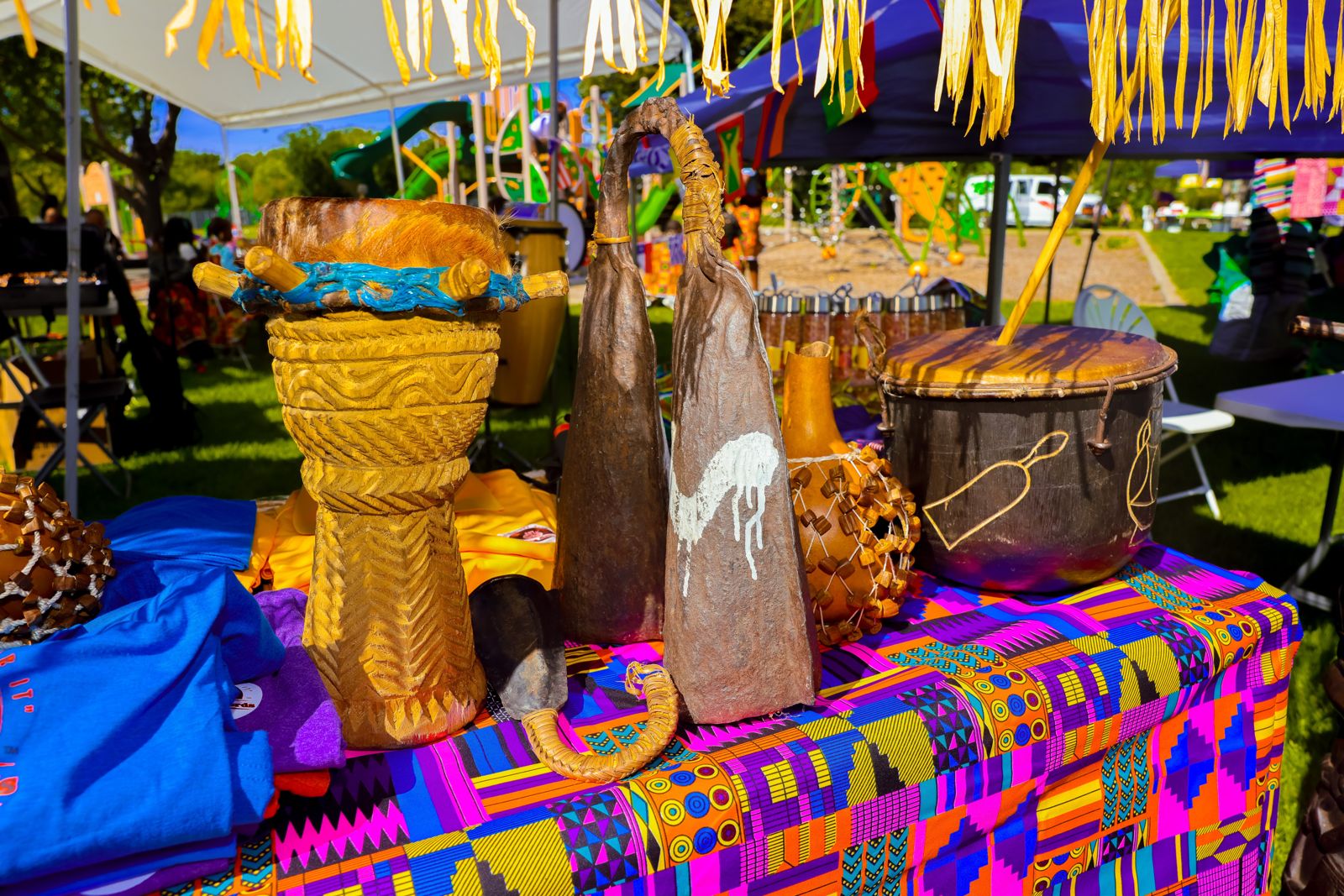 Close-up of a carved standing drum, metal gongs and a beaded gourd shaker